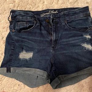 Dark wash stretch denim shorts with distressed patches